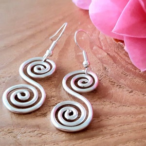 May include: A pair of silver-toned earrings featuring a double spiral design connected in an S-shape. Each earring is suspended from a standard silver-toned metal hook wire, creating a continuous, flowing metallic form with a smooth, polished finish.