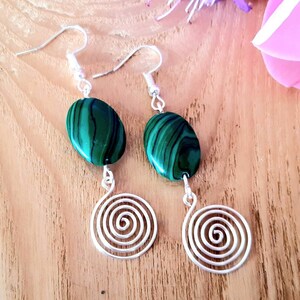 May include: A pair of silver earrings with green malachite stone drops and a spiral design.