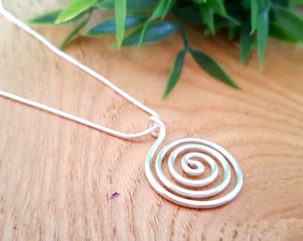 May include: A silver necklace with a spiral pendant. The pendant is made of wire and has a simple, modern design.