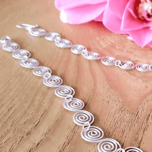 Close up details of the Celtic Silver spiral necklace on a wooden surface
