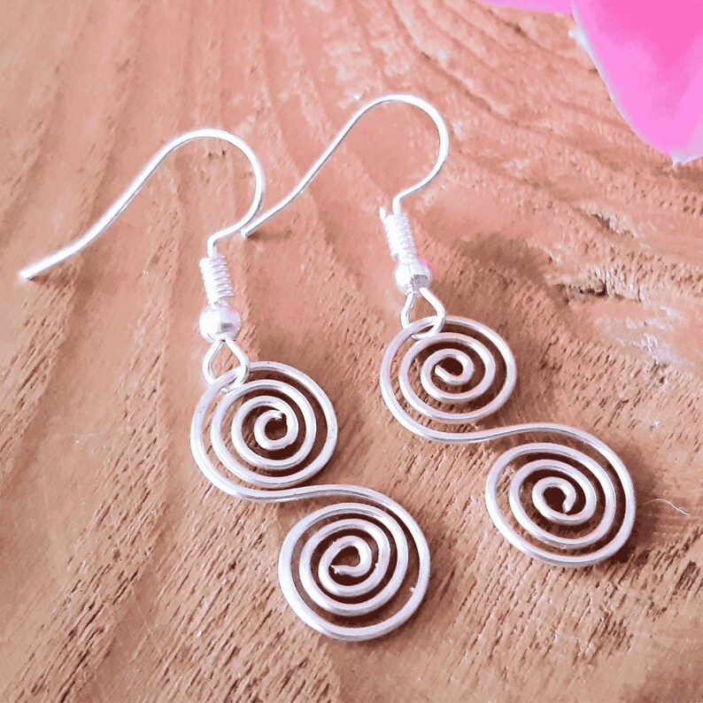 Close up view of a pair of Celtic Silver spiral earrings on a wooden surface