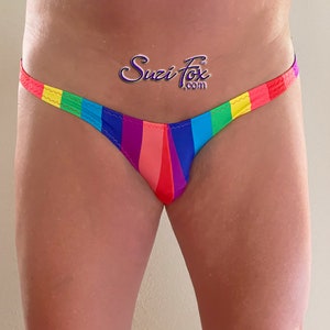 May include: Rainbow striped men's underwear with a low rise cut. The underwear has a thin elastic waistband with a yellow, green, blue, purple, pink, red, and orange stripe pattern. The text "Suzi Fox .com" is printed on the front of the underwear.