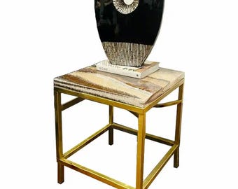 May include: A gold metal side table with a square top made of brown and white marble. A black and white vase with a circular cutout sits on top of the table.