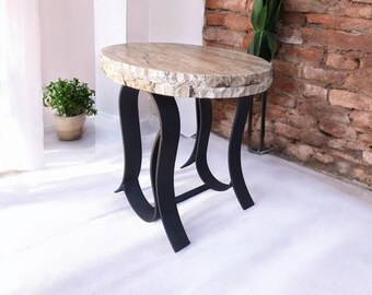 May include: A small, decorative side table with a natural stone top and black metal legs. The oval tabletop is approximately 24 inches in diameter. The legs have a unique, curved design, adding a modern touch to the piece.