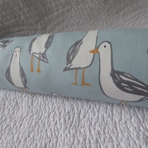 May include: A blue fabric with a white background featuring a repeating pattern of seagulls. The seagulls are white with grey wings and orange beaks and feet.