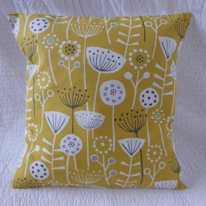 May include: A yellow cushion with a white and grey floral pattern. The cushion features a repeating design of stylised flowers with grey centres and white petals.