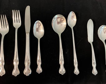 May include: A set of eight silver-plated flatware pieces, including forks, knives, and spoons. The handles are ornate with a floral design.