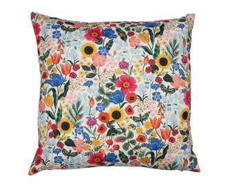 May include: A white pillow with a floral pattern featuring a variety of colorful flowers, including red, pink, yellow, blue, and green.