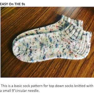 Puede incluir: Un par de calcetines blancos con un patrón moteado multicolor. Los calcetines están tejidos con una aguja circular pequeña de 9 pulgadas. "EASY On THE 9s" está escrito en la parte superior de la imagen.