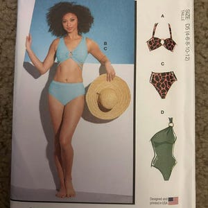 May include: McCall's M8329 sewing pattern envelope featuring a light blue two-piece swimsuit with a ring detail, a straw hat, and illustrations of alternative swimsuit designs including a patterned bikini top, bikini bottoms, and a one-piece swimsuit.