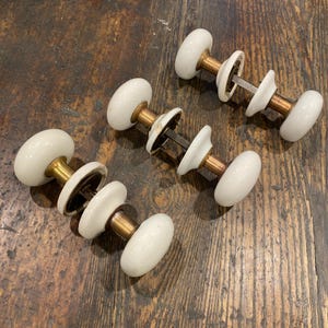White Porcelain Door Knobs with Brass Shanks and Porcelain Rosettes.  SOLD SEPARATELY.  Antique Victorian.