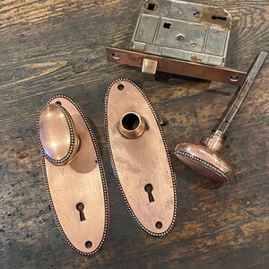 Herrajes antiguos para puertas de Yale & Towne. Pomos y placas traseras ovaladas con cuentas. Cerradura con pestillo. Patentado en 1891. Estilo victoriano.