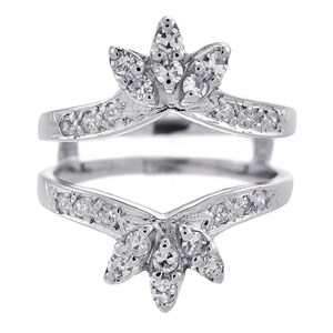 Könnte beinhalten: Ein silberner Ring mit einem zarten floralen Design. Der Ring ist mit kleinen, klaren Diamanten besetzt und hat eine V-förmige Öffnung in der Mitte.
