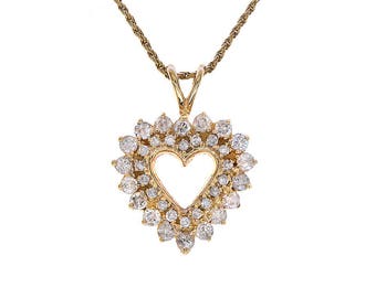 Puede incluir: Un collar de oro con un colgante de corazón de diamantes. El corazón está abierto en el centro y rodeado de diamantes más pequeños.