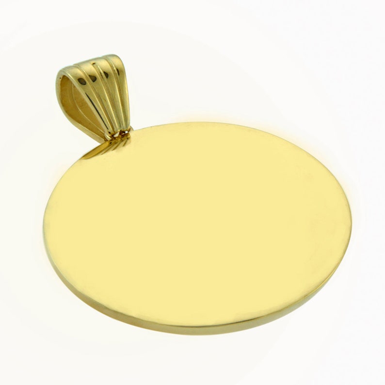 May include: A round, gold-colored pendant with a smooth, polished surface. The pendant has a simple, elegant design and is perfect for engraving.