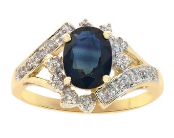 Op de afbeelding: Een gouden ring met een grote ovale blauwe saffier, omringd door kleinere diamanten. De ring heeft een delicaat en ingewikkeld ontwerp.