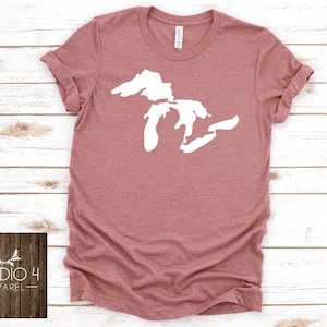 May include: A mauve coloured t-shirt with a white outline of the Great Lakes on the front. The shirt is made of a soft, comfortable material and has a crew neck.