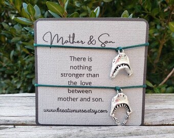 May include: A gray card with the words "Mother & Son" and a message about the love between a mother and son. Two shark-shaped charms hang from green cords. The website address www.kreatwnurse.etsy.com is at the bottom.