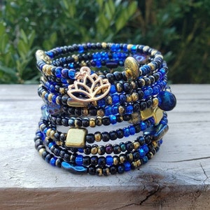 May include: A multi-strand beaded bracelet with blue and black beads, gold accents, and a gold lotus charm.
