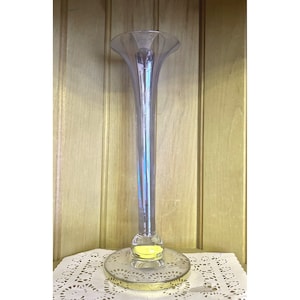 May include: A tall, clear glass vase with a flared top and a gold-rimmed base. The vase has a textured, ribbed design.