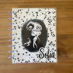 May include: A white planner cover with a black and white illustration of a scorpion and a woman with a star pattern background. The name "Sofia" is written in black cursive at the bottom.