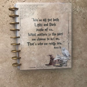 May include: A quote from the Harry Potter series by Sirius Black, printed on a planner with a white owl and a wizard's hat on a stack of books. The quote reads, "We've all got both Light and Dark inside of us. What matters is the part we choose to act on. That's who we really are."