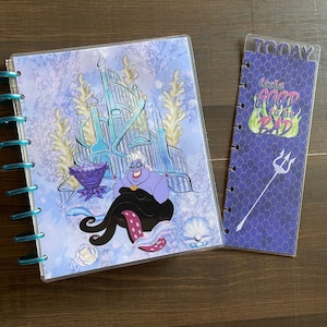 May include: A planner and bookmark set featuring Ursula from The Little Mermaid. The planner has a blue cover with Ursula and an underwater scene. The bookmark reads "Today feels good to be bad" with a trident illustration.