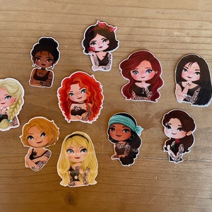 May include: Set of nine illustrated stickers featuring Disney princesses with tattoos. Each sticker features a different princess with a unique tattoo design. The princesses are depicted in a cartoon style with bright colors and expressive features.