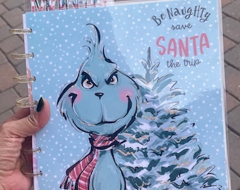 May include: A blue and green Grinch-themed planner cover with the text "Be Naughty save SANTA the trip" and the name "Danielle" at the bottom. The Grinch is holding a stack of wrapped presents.
