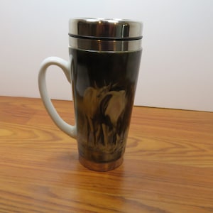 May include: A white ceramic travel mug with a stainless steel lid and a black and white image of two horses on the side.