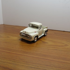 May include: A white vintage pickup truck toy model. The truck has a black grill and black wheels.