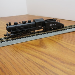 May include: A black model train engine with a tender car, the engine has the number 3283 on the side, the train is on a track.