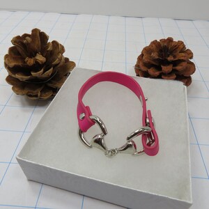 May include: A pink leather bracelet with a silver horse bit charm.