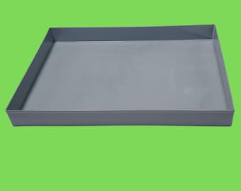 Puede incluir: Una bandeja rectangular de plástico gris. La bandeja está vacía y tiene una superficie lisa.
