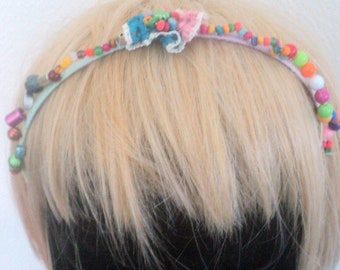 Metal headband covered with multicolored skeins and beads, in the middle flower blue, orange and pink ribbon. Handmade headband