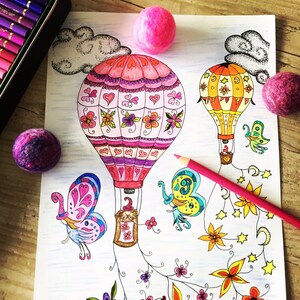 K&ouml;nnte beinhalten: Eine Malvorlage mit zwei Hei&szlig;luftballons, einem rosa und einem gelben, mit aufwendigen Designs. Die Ballons sind von Schmetterlingen, Blumen und Sternen umgeben. Die Seite liegt auf einer Holzoberfl&auml;che mit rosa Wollkugeln.