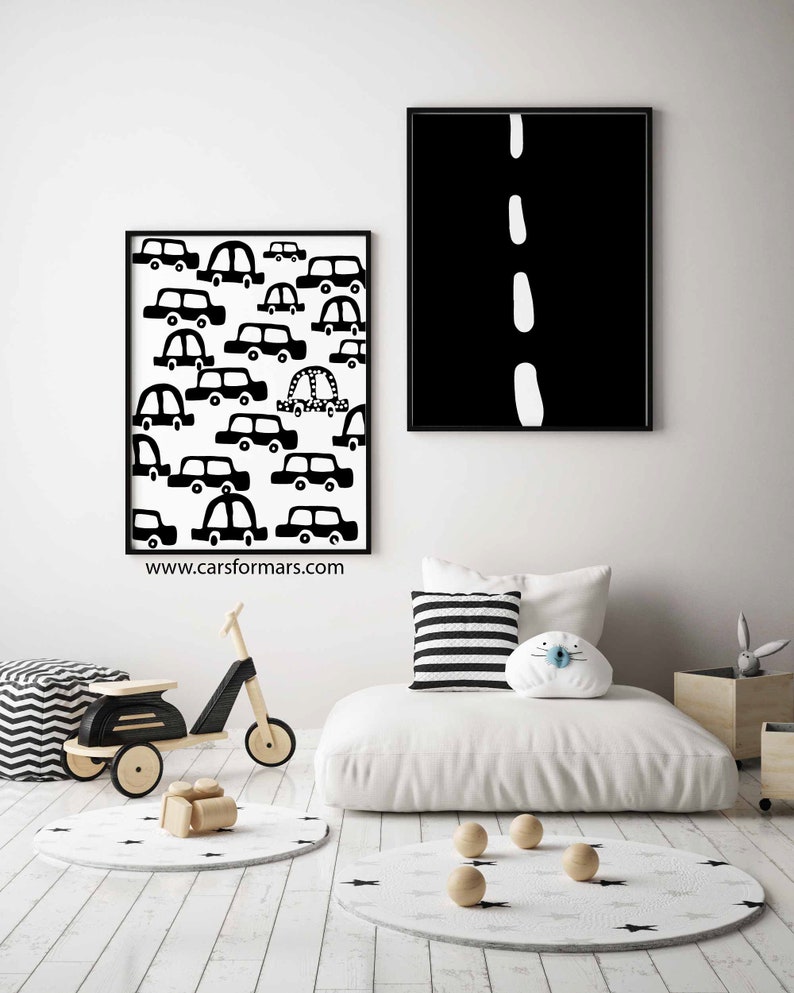 Puede incluir: Ilustraciones en blanco y negro de coches y una carretera en dos impresiones enmarcadas. Las impresiones cuelgan de una pared blanca sobre un fut&oacute;n blanco con almohadas a rayas blancas y negras. El fut&oacute;n est&aacute; sobre un suelo de madera blanca con una alfombra de estrellas blancas y negras.