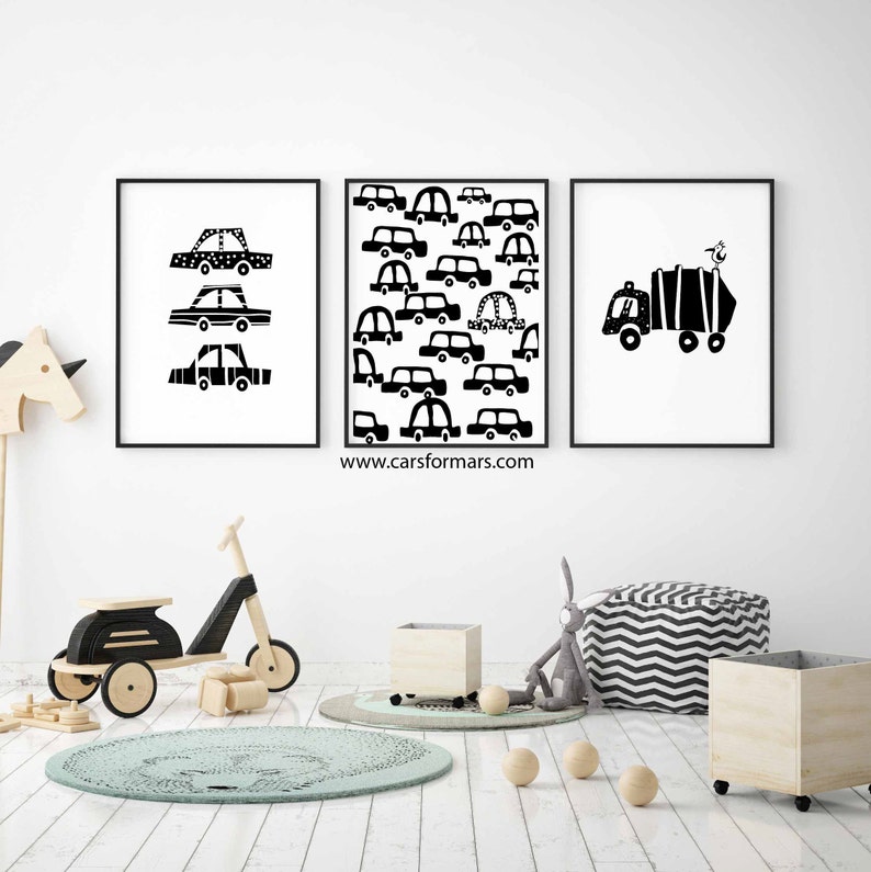 Puede incluir: Tres impresiones enmarcadas en blanco y negro de coches y camiones. Las impresiones est&aacute;n colgadas en una pared blanca en una habitaci&oacute;n infantil. La habitaci&oacute;n tiene un suelo de madera, una alfombra y un scooter de juguete de madera.