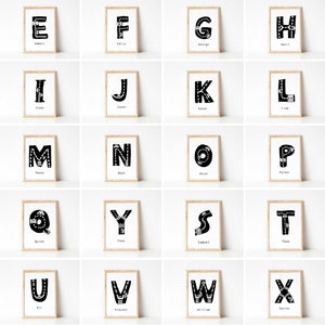 May include: A set of 26 alphabet posters featuring black letters with a road design on a white background. Each poster has a name below the letter. The posters are framed in a light wood frame.