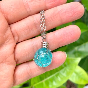 May include: A turquoise gemstone pendant necklace with a silver chain. The gemstone is encased in a silver wire cage.