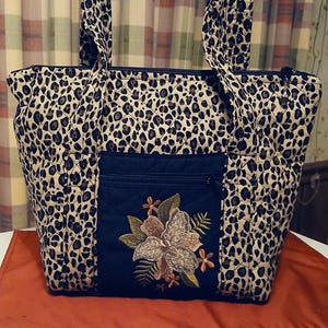 2 strap quilted purse includes makeup pouch included 11 pockets leopard print with leopard emb flower