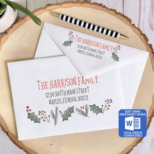 May include: A white envelope with a red and green holly border and the text "THE HARRISON FAMILY 1234 SOUTH MAIN STREET NAPLES, FLORIDA 30123" printed on it. The envelope is on a wooden surface. The text "EDIT USING MICROSOFT WORD W MAIL MERGE COMPATIBLE" is printed in the bottom right corner.