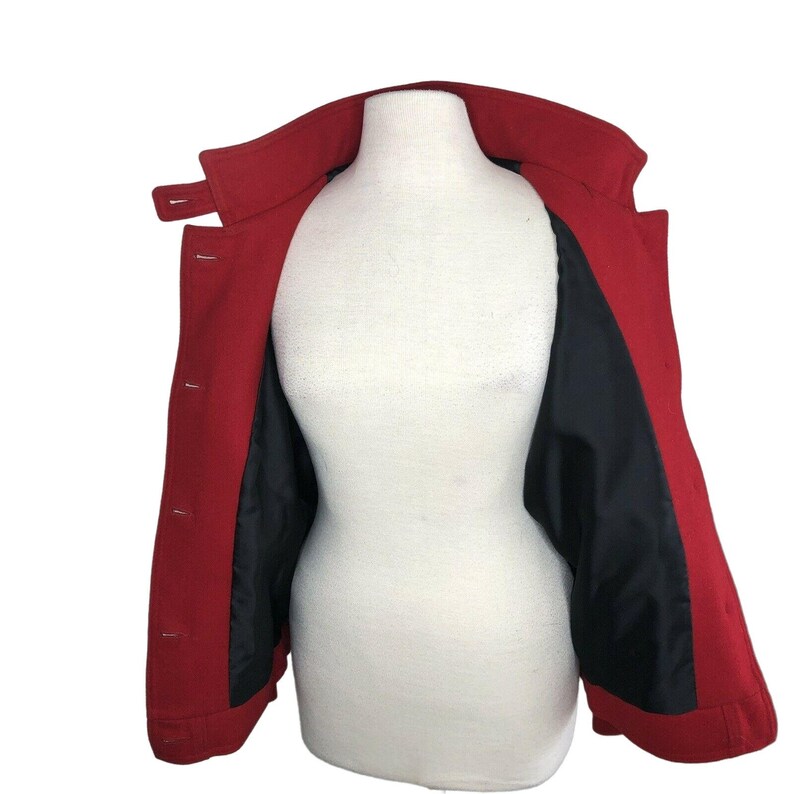 May include: A red wool coat with a black lining. The coat is open and the lining is visible. The coat has a collar and buttons.