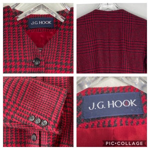 Puede incluir: Una chaqueta de punto roja y negra a cuadros con cuello en V y cierre de botones. La chaqueta tiene una etiqueta que dice "J.G. Hook".