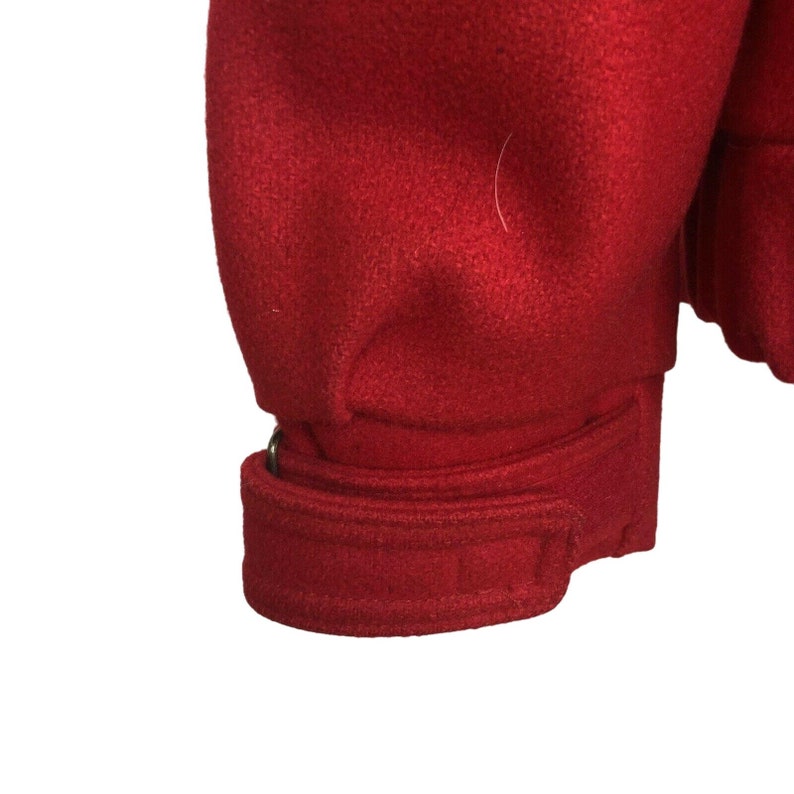 May include: Red wool jacket with a belt detail on the sleeve.