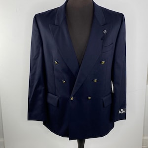 May include: A navy blue double-breasted blazer with gold buttons. The blazer has a single button on the left side of the chest and a label on the right sleeve that reads "Paul Smith".
