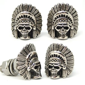 Może przedstawiać: Cztery srebrne ozdoby motocyklowe w kształcie czaszki z indiańskim nakryciem głowy. Ozdoby są przymocowane do śruby.