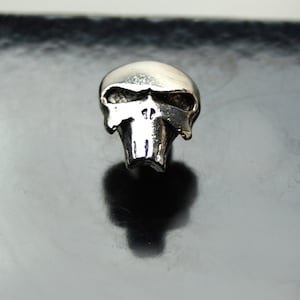 Op de afbeelding: Een zilveren schedelbedel met een gedetailleerd ontwerp. De schedel heeft een prominente kaaklijn en een gedetailleerd gezicht.