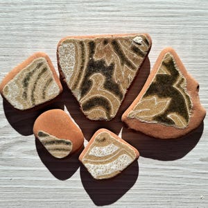 May include: Five ceramic tiles with a brown and white glaze. The tiles have a unique, abstract design with swirls and lines.