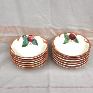 May include: A set of ten vintage ceramic bowls with a brown rim and a white interior. Each bowl features a red apple with green leaves on a white background.